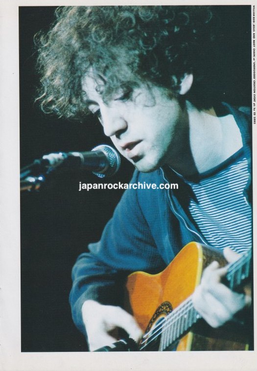 Photo of William Reid of The Jesus And Mary Chain on stage with acoustic guitar